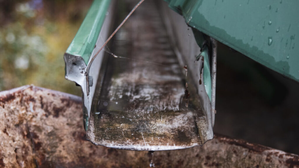 A close-up of a metal roof with water droplets cascading down its surface.